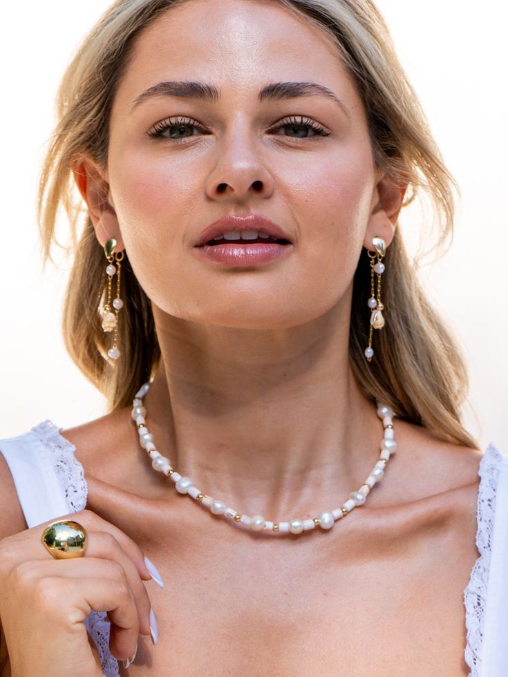 The Shell and Pearl Dangle Earrings are an exquisite blend of natural elegance and refined luxury. They feature a delicate gold chain that provides a lightweight framework. Attached to the chain are small pearls that catch the light beautifully, Interspersed with the pearls are small, polished seashells, which bring a subtle, beach-inspired charm to the design. Dangle Pearl Earrings With Adjustable Chain, Feminine Pearl Earrings With Pearl Chain, Feminine Gold Pearl Earrings With Pendant, Feminine Gold Pearl Pendant Earrings, Gold Pearl Pendant Earrings In Feminine Style, Delicate Pearl Chain Dangle Earrings, Feminine Pearl Chain Earrings, Delicate Pearl Chain Earrings, White Pearl Earrings With Adjustable Chain