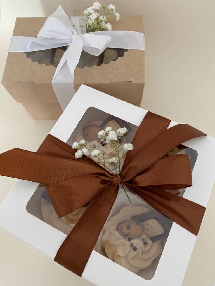 two boxes with brown ribbon and flowers in them