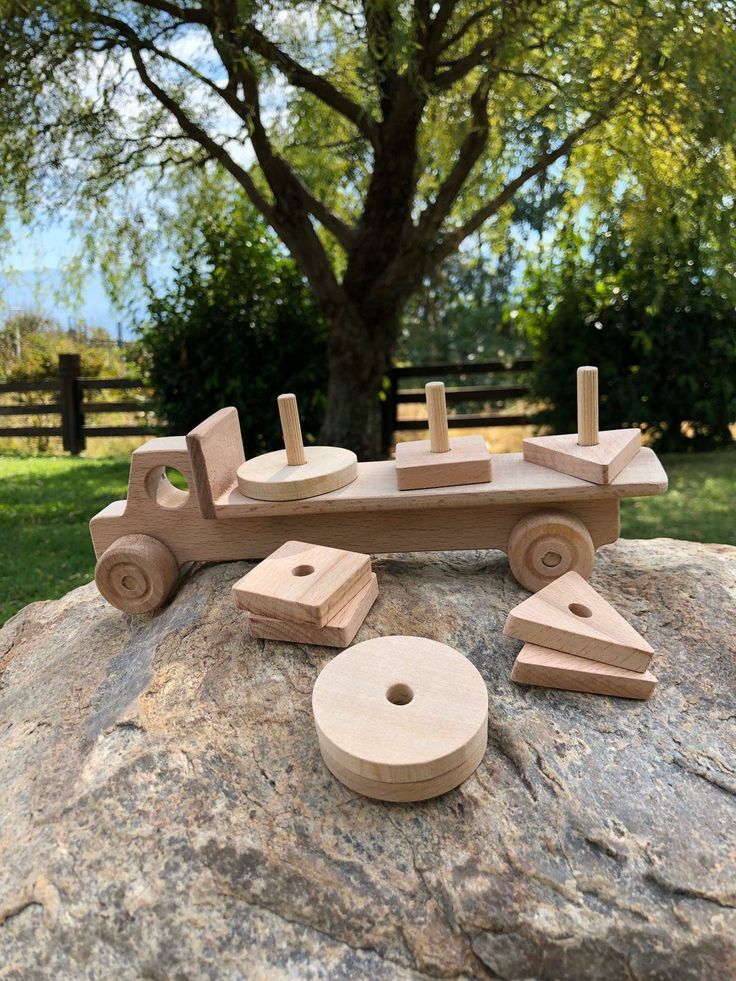 a wooden toy truck sitting on top of a rock