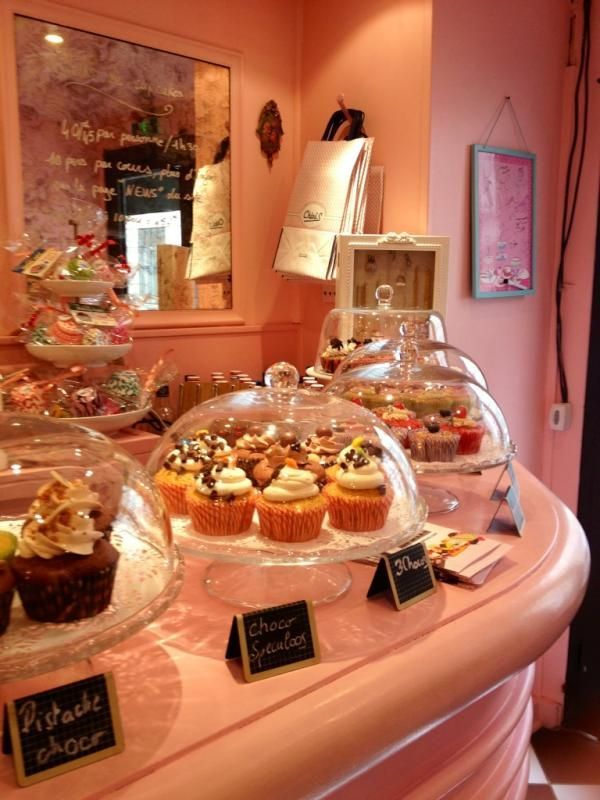 there are many cupcakes on display in the glass dome cases at this bakery