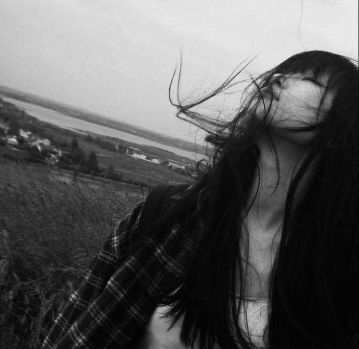 a woman with long hair standing in a field