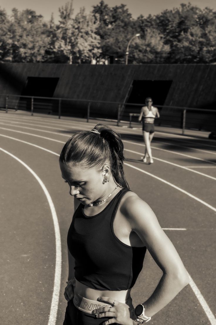 a woman standing on a tennis court with her hands on her hips and looking down