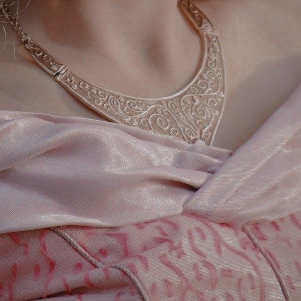 a woman wearing a pink sari with intricate designs on the blouse and neckline