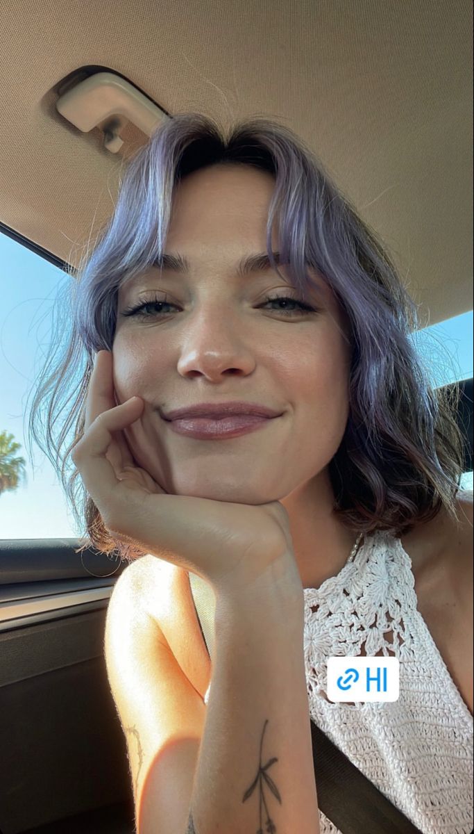 a woman sitting in the back seat of a car with her hand on her chin