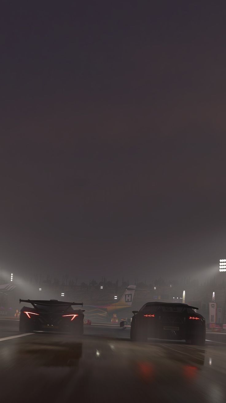 two cars driving down the road at night in foggy weather, with lights on