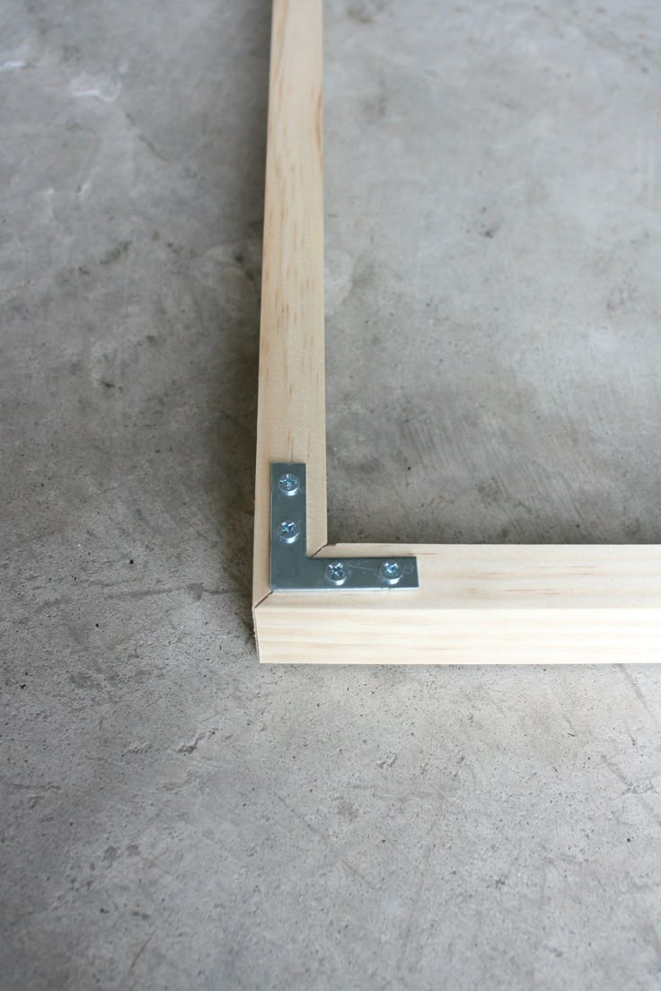 a wooden frame sitting on top of a cement floor next to a pair of scissors