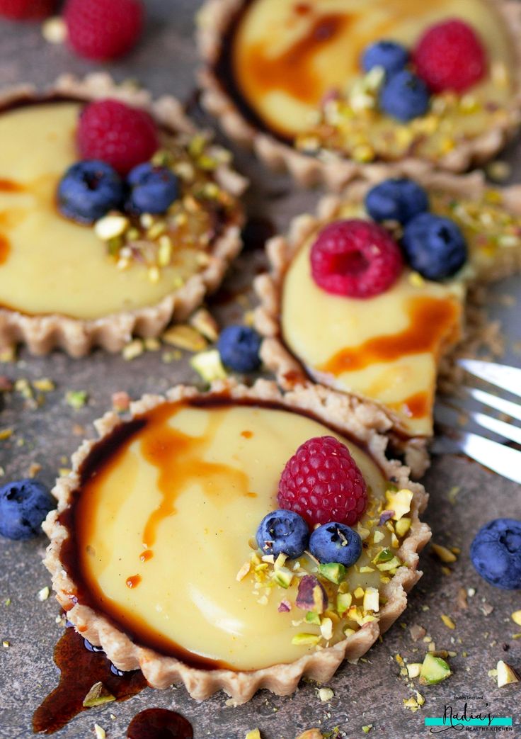 small desserts with berries and other toppings sit on a table next to a fork