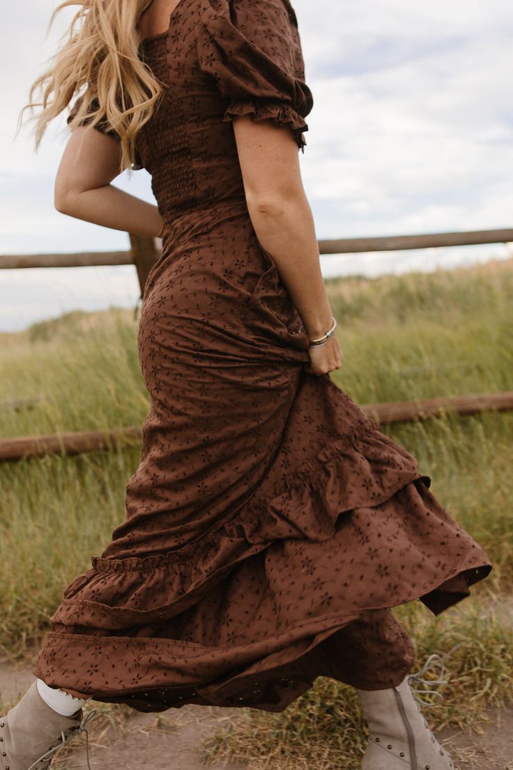 Say hello to your new favorite women's dress! The Rachel is a lovely brown maxi-length dress featuring a classic ivy silhouette, flattering square neckline and short puff sleeves. Perfectly paired with your favorite boots. Enjoy the magic of fall and beyond in this stunning outfit. Maxi Dress With Lace Up Boots, Brown Bohemian Dress With Square Neck, Brown Square Neck Dresses With Ruffles, Fitted Brown Maxi Dress With Short Sleeves, Fall Vintage Brown Dress, Fall Barn Wedding Guest Dress, Brown Bohemian Square Neck Dress, Cottagecore Brown Dress For Spring, Cowgirl Boots And Dress