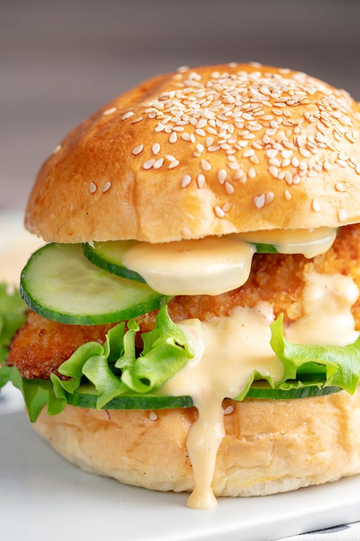 a chicken breast burger with cucumber and lettuce on a white plate