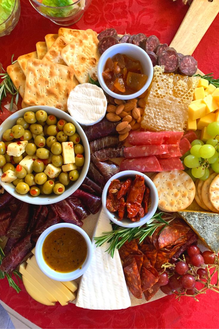 a platter filled with cheese, olives, crackers and other food items