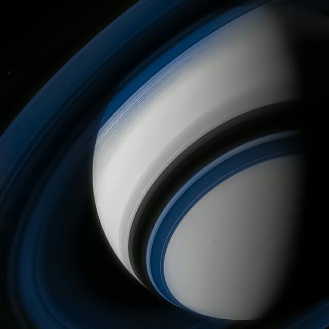 an image of saturn taken from space with the moon visible in the center and blue rings around it