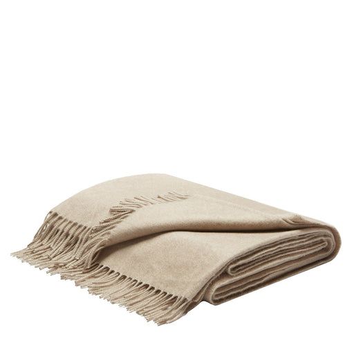 a beige blanket with fringes on the bottom and one end folded up to show it's logo