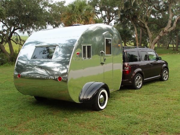 two cars are parked next to each other in the grass near a trailer with a camper on it