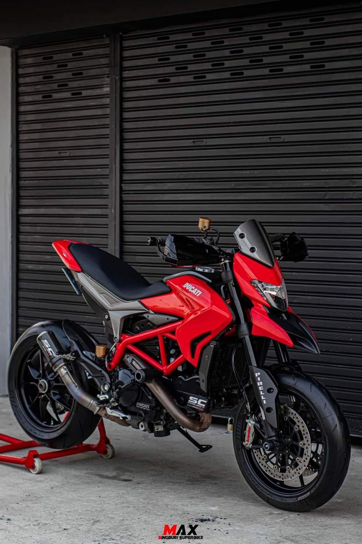 a red motorcycle parked next to a garage door