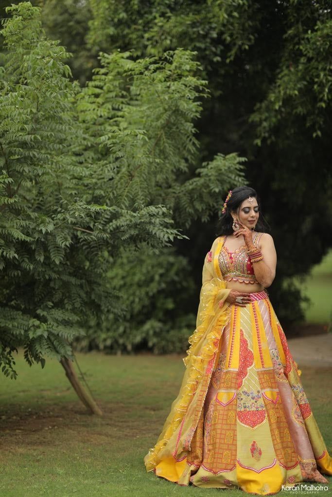 a woman in a yellow and red dress posing for the camera with trees behind her