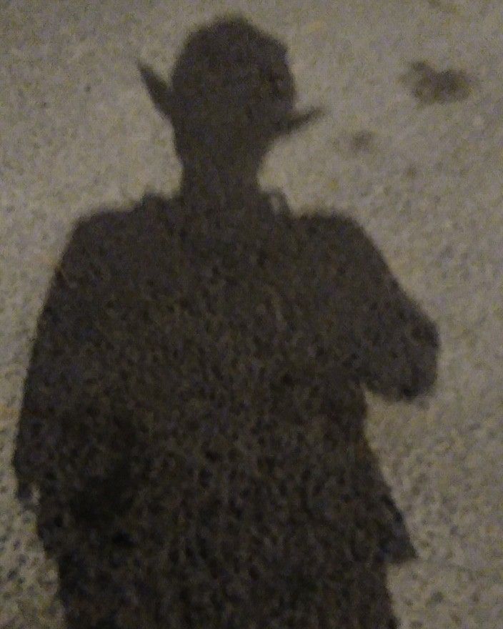 a shadow of a man with a hat and cane on the ground in front of him