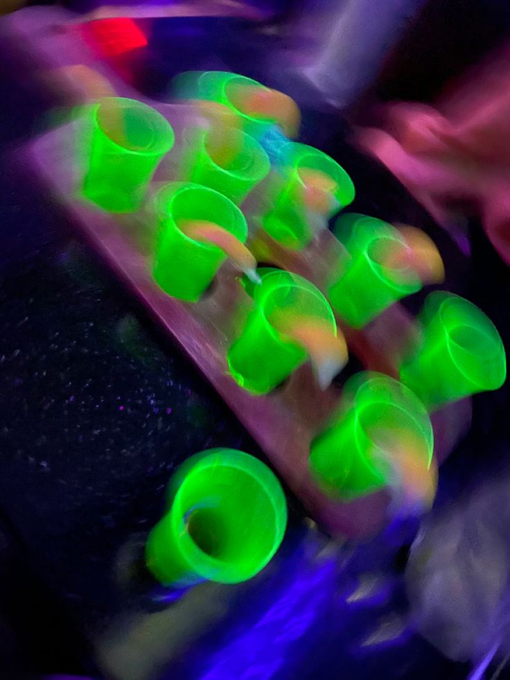 blurry photograph of neon colored cups on top of a table in front of a person