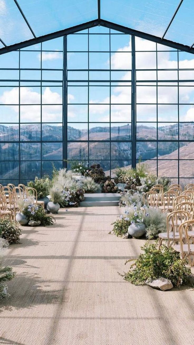 an indoor wedding venue with rows of chairs set up for the ceremony and flowers on the aisle