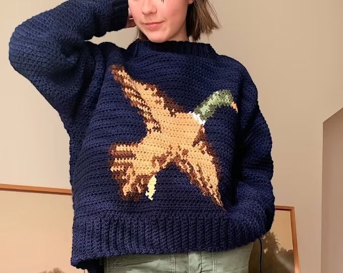 a woman wearing a blue sweater with an image of a bird on it