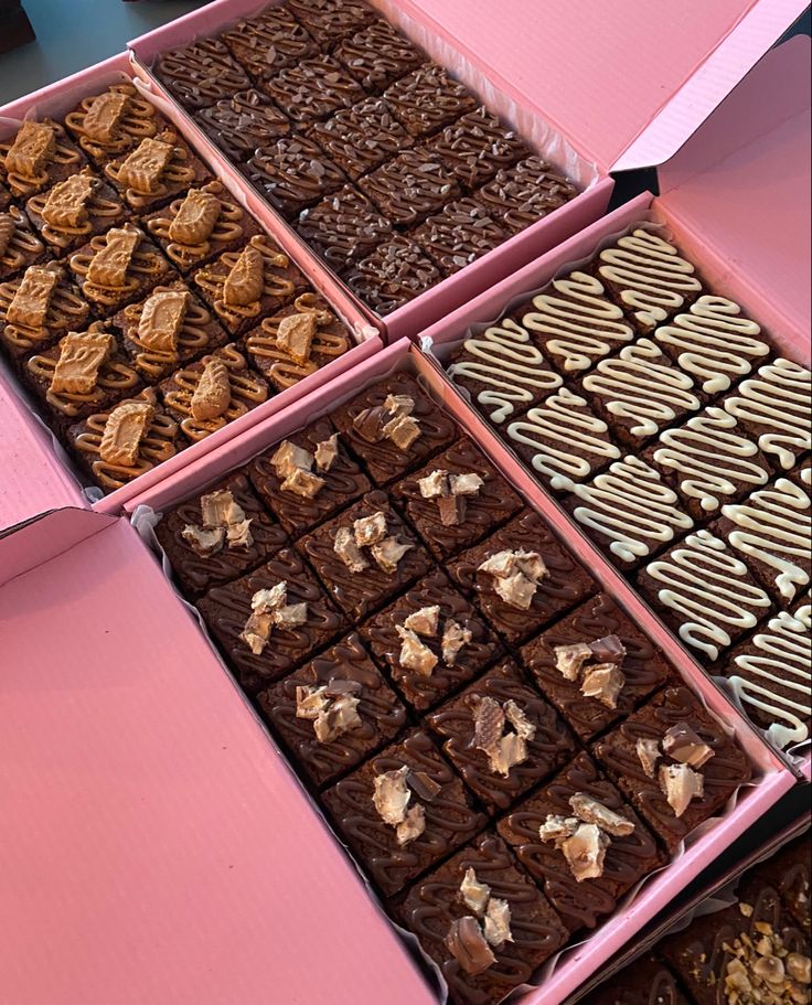 four pink boxes filled with different types of chocolates and cookies on top of each other