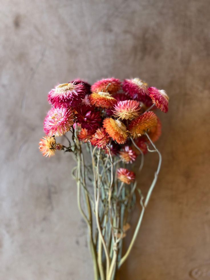 a bunch of flowers in a vase on a table next to a wall and floor