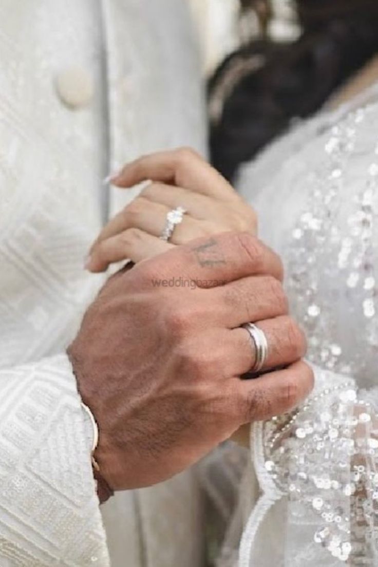 a man and woman are holding hands with each other while wearing wedding rings on their fingers