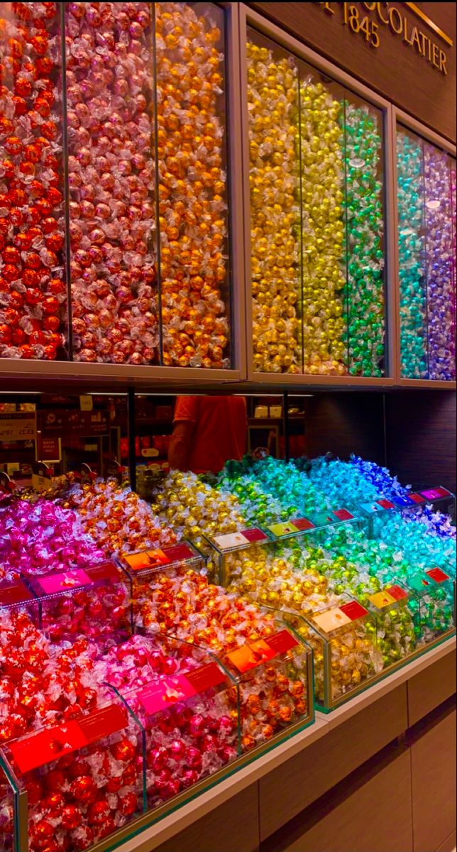 there are many different colored candies in the display case at this candy store that sells them