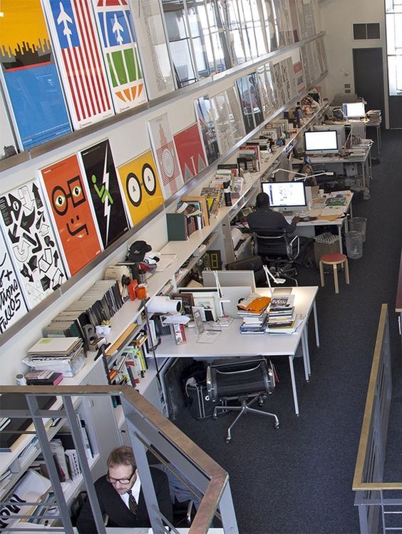 an office filled with lots of desks and computer screens on the wall next to each other