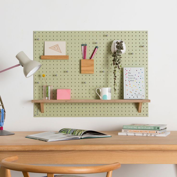 a wooden table topped with books next to a wall mounted pegboard covered in magnets