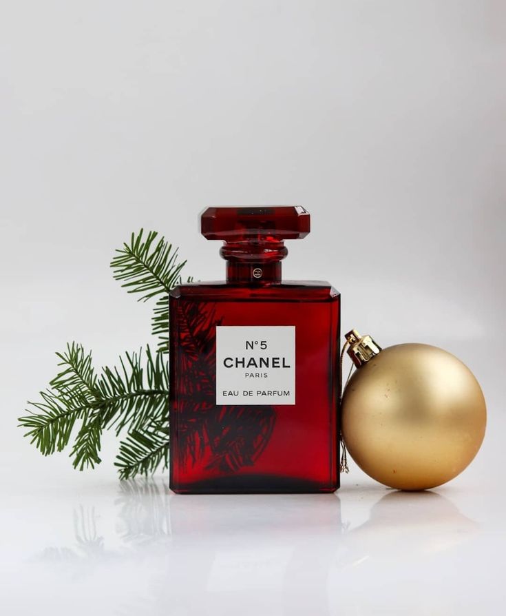 a bottle of chanel perfume next to a christmas ornament on a white surface