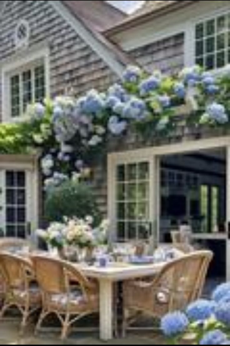 an outdoor dining area with blue flowers and greenery