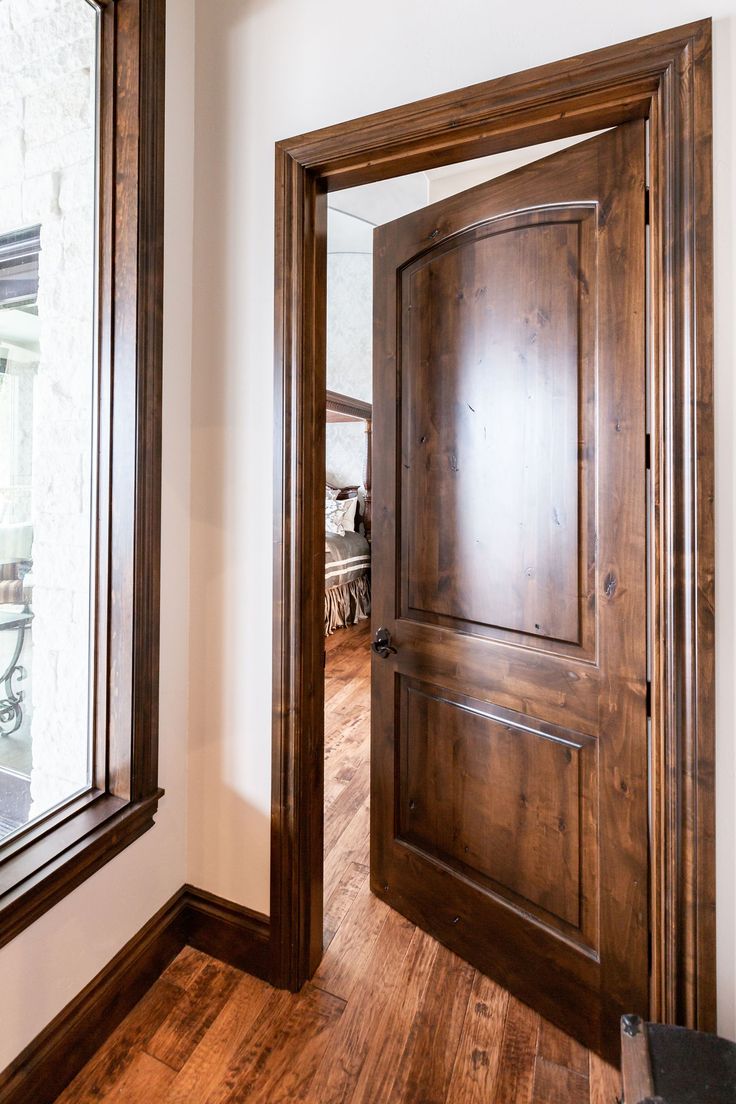 an empty room with a wooden door and large mirror on the wall next to it