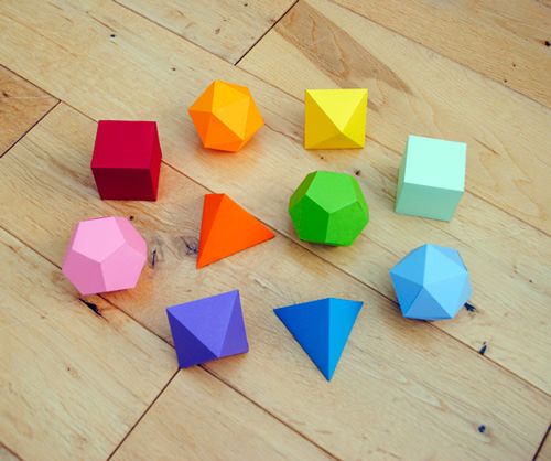 there are many different colored shapes on the wooden floor, including cubes and triangles