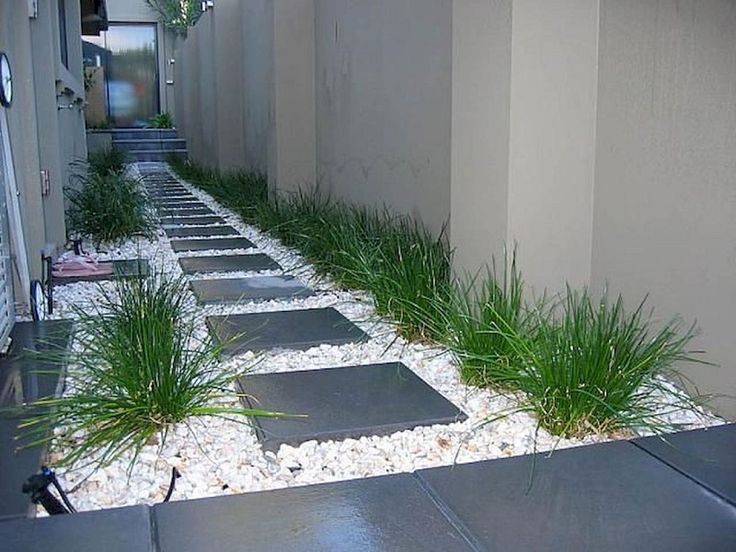 a walkway made out of stones with grass growing between it and a building in the background