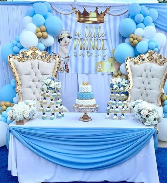 a table topped with blue and white balloons next to a cake on top of a table