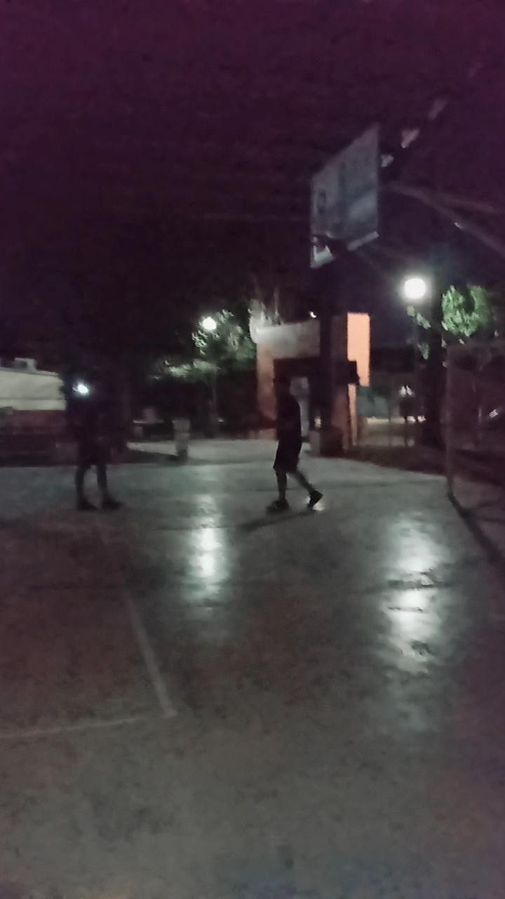 some people are playing basketball at night in the dark with no one on it's shoes