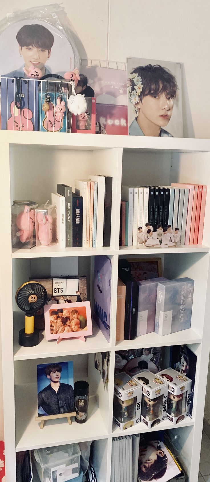 a book shelf filled with lots of books next to a clock and pictures on the wall