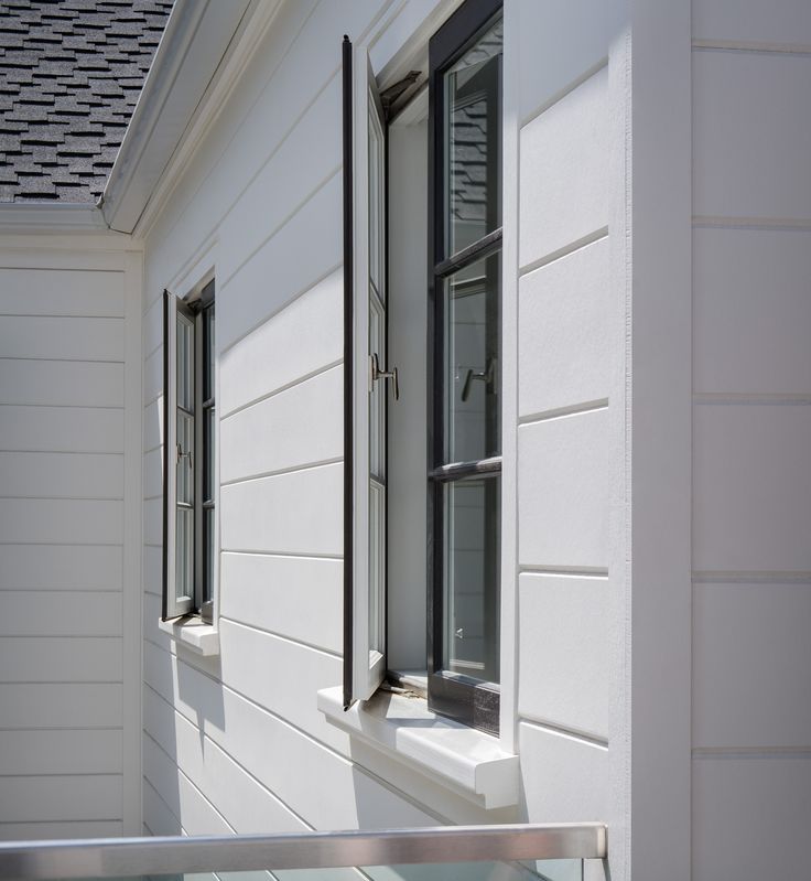 two windows on the side of a white house