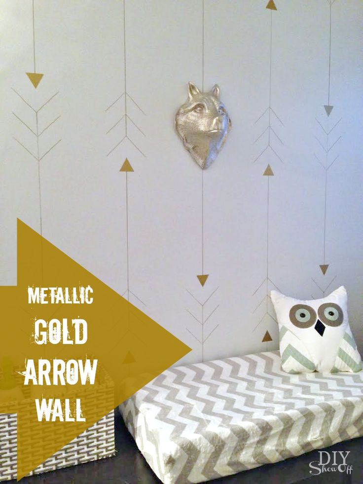 an owl pillow sitting on top of a bed next to a wall with gold arrows