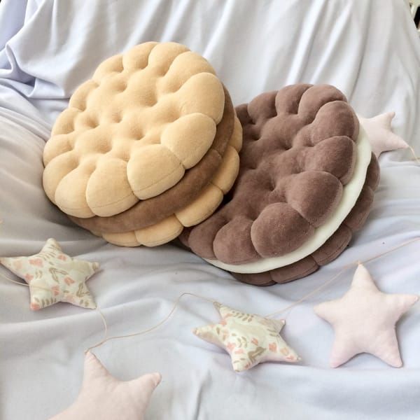 three cookies and two biscuits on a bed with stars around them, one cookie has been made to look like the other