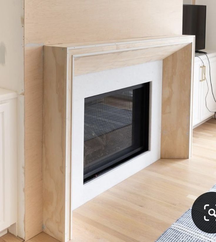 a white fireplace in a room with wood floors