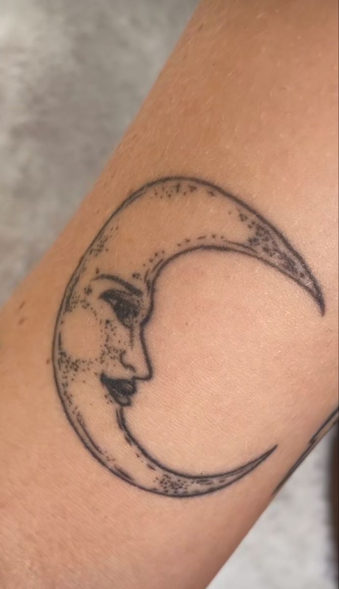 a woman's arm with a crescent moon tattoo on it