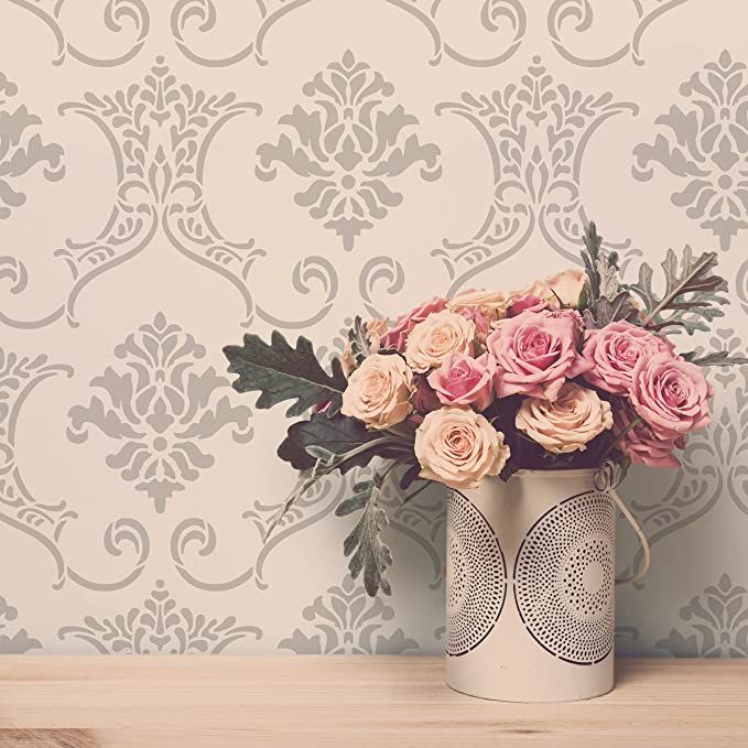 a bouquet of pink roses in a white vase on a wooden table against a wallpapered background