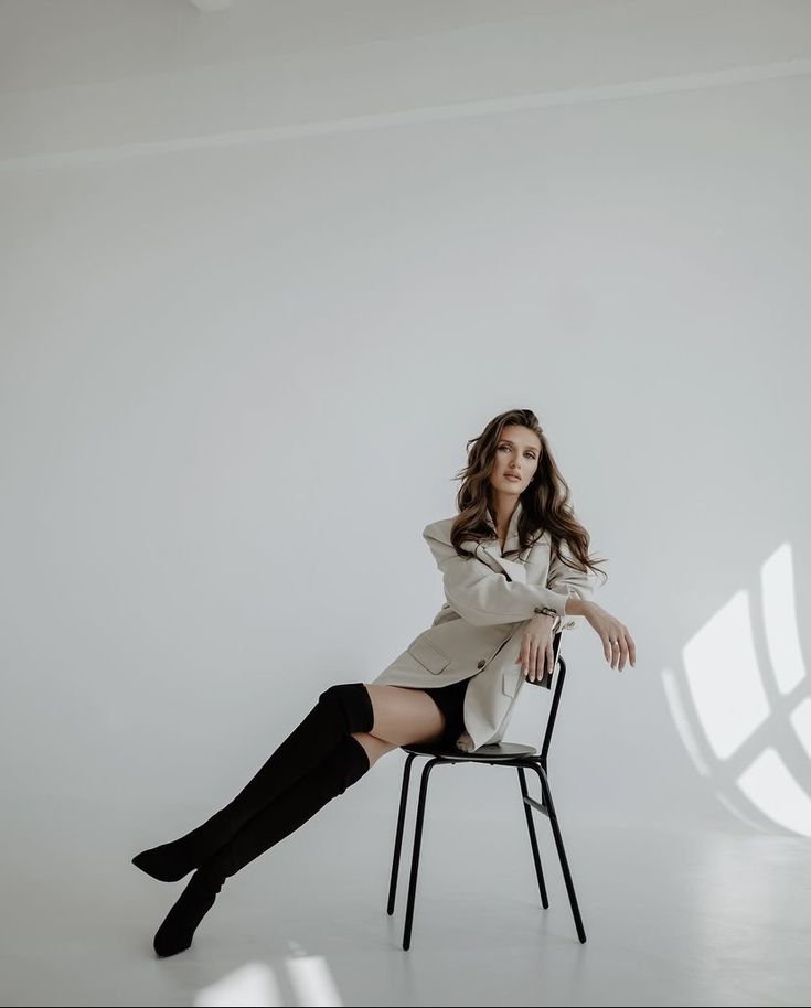 a woman sitting on top of a chair with her legs crossed and wearing black boots