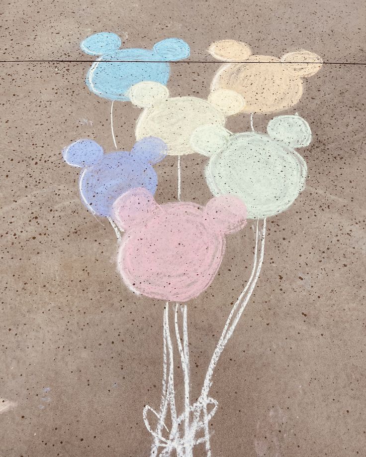 a chalk drawing of mickey mouse balloons on the ground