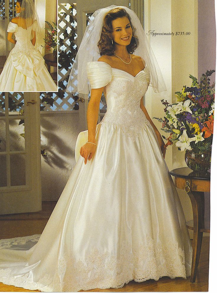 a woman wearing a wedding dress and veil in front of a mirror with flowers on it