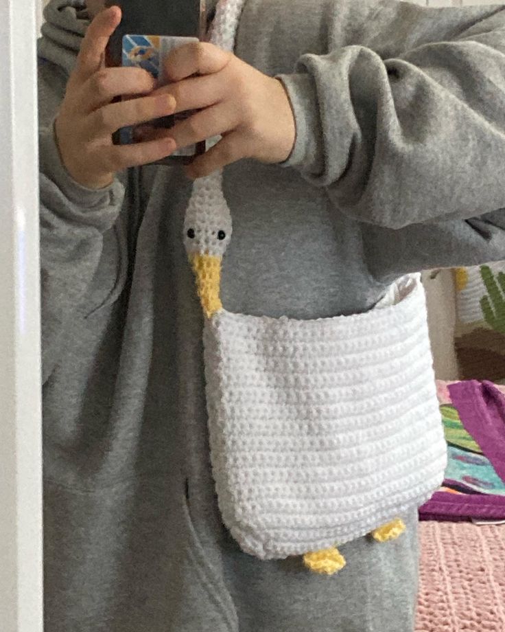 a person taking a selfie in front of a mirror with a crocheted bag