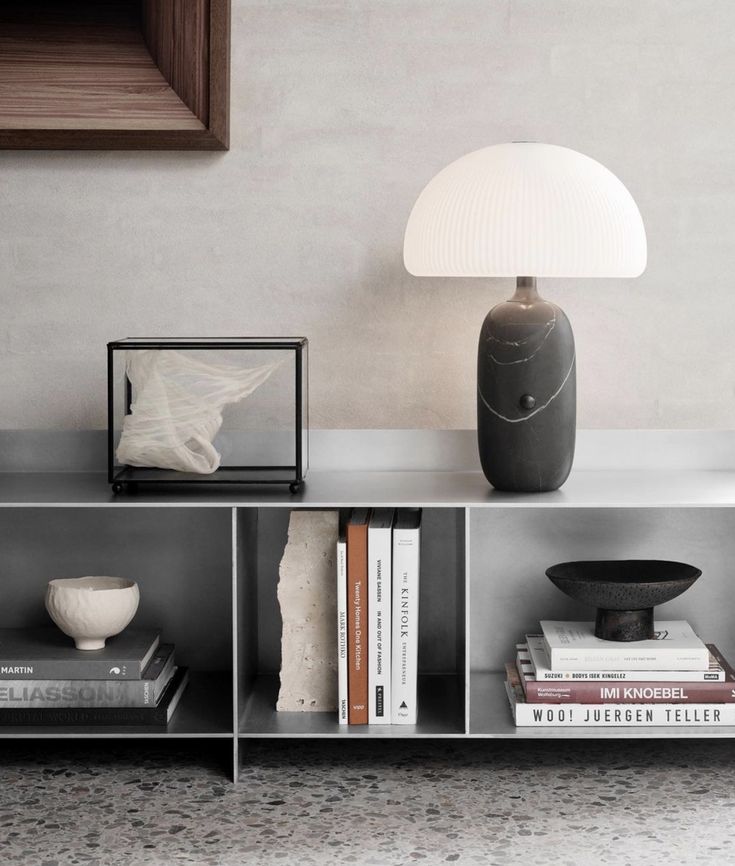 a table with books and a lamp on it next to a wall in a room