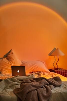 a laptop computer sitting on top of a bed under a rainbow colored light in a bedroom