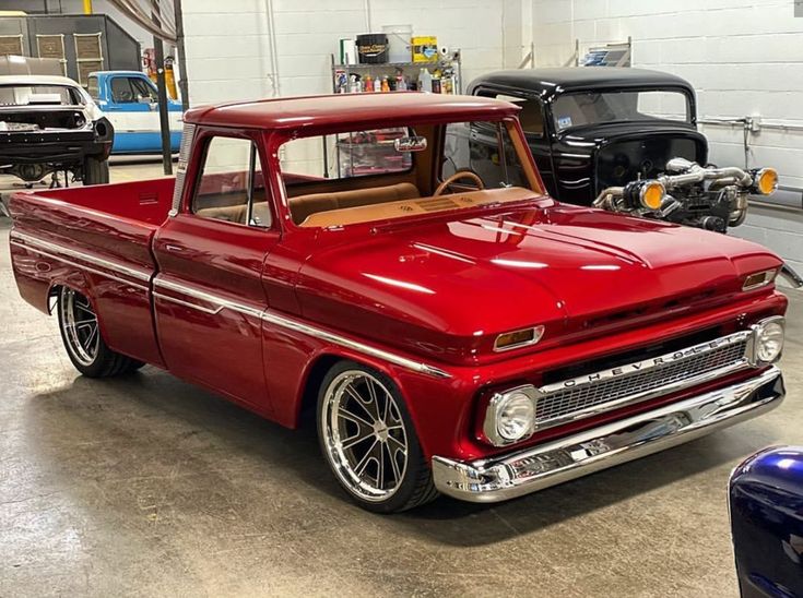 an old red pickup truck parked in a garage